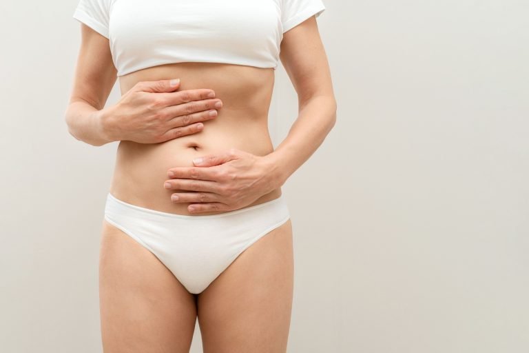 Woman holding her belly with hands suffering from abdominal pain,stomach ache or indigestion